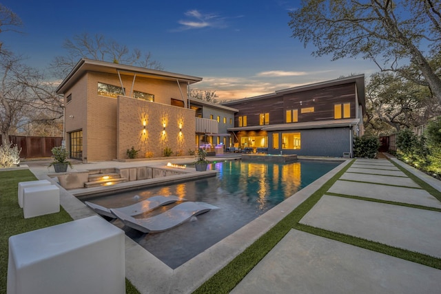 pool at dusk featuring a fenced in pool, fence, a hot tub, and a patio