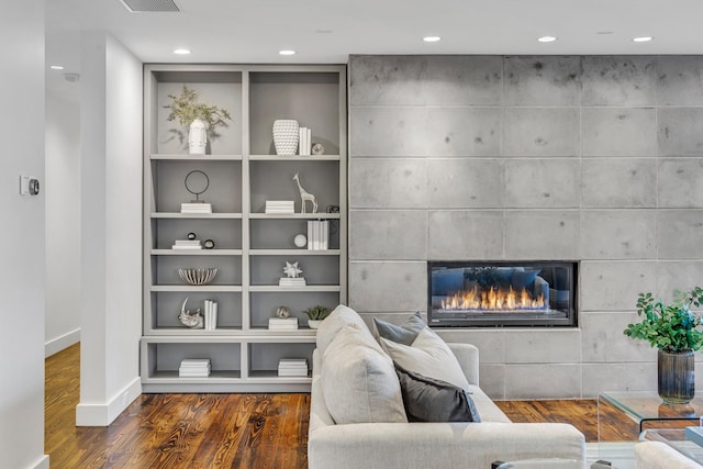 living area with baseboards, a tile fireplace, dark wood-style floors, built in shelves, and recessed lighting