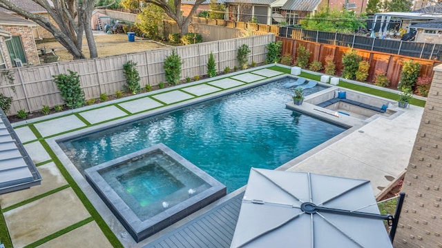 view of swimming pool with a fenced backyard and a pool with connected hot tub