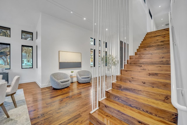 staircase featuring a high ceiling, wood finished floors, and baseboards