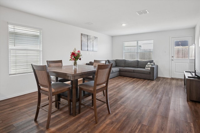 dining space with dark wood-style floors, visible vents, and baseboards