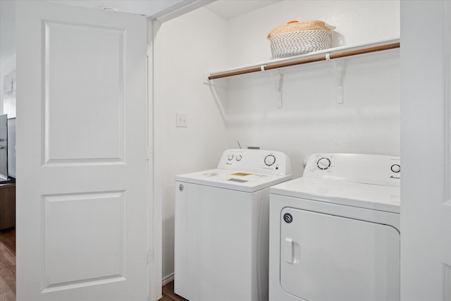 washroom with wood finished floors, laundry area, and separate washer and dryer