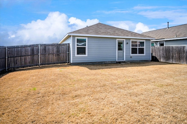 back of property featuring a fenced backyard, a yard, and roof with shingles