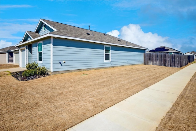 view of side of home with a lawn and fence