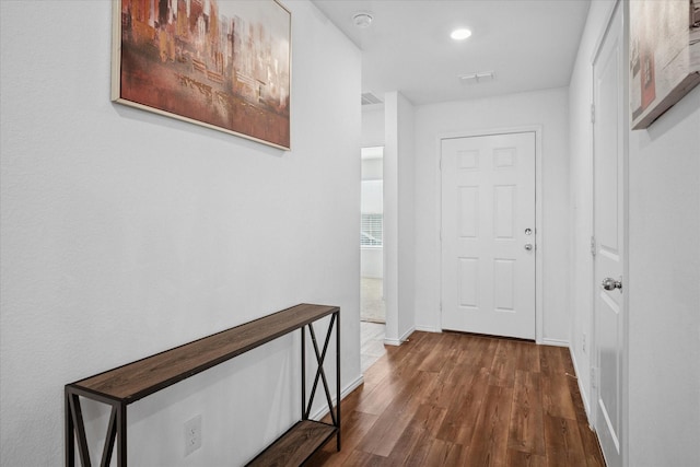 corridor with dark wood finished floors, visible vents, and baseboards