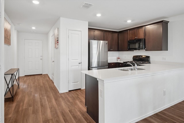 kitchen with visible vents, wood finished floors, light countertops, black appliances, and a sink