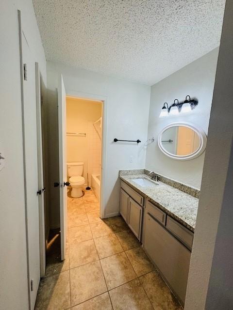 full bathroom with tile patterned flooring, a textured ceiling, toilet, and vanity