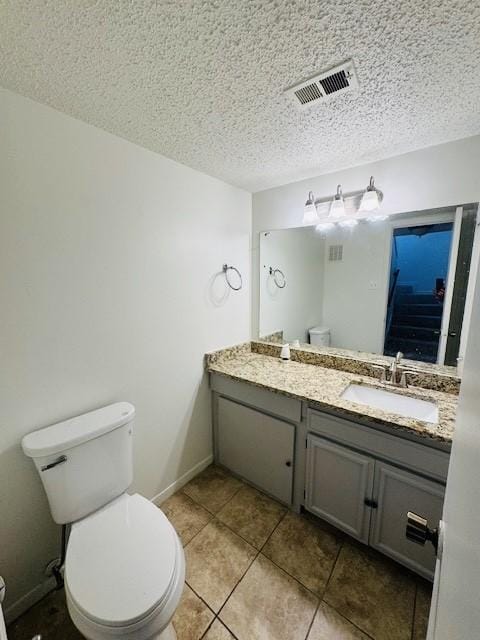 bathroom with visible vents, toilet, vanity, a textured ceiling, and baseboards