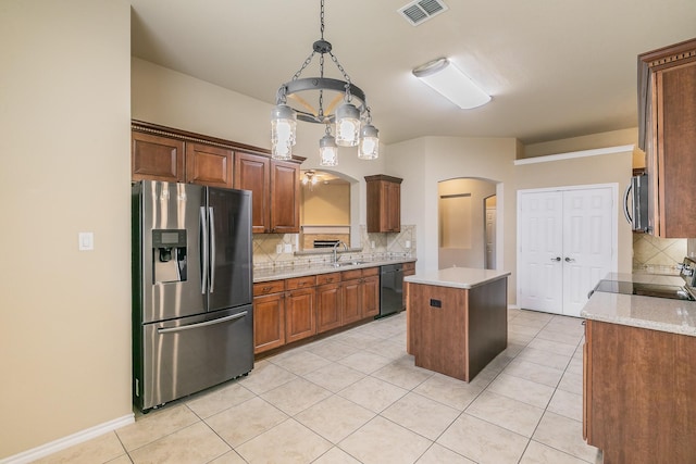 kitchen with visible vents, arched walkways, a sink, appliances with stainless steel finishes, and a center island