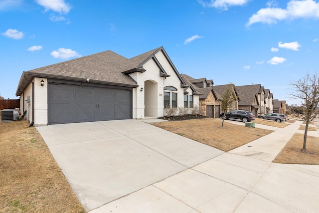 french country style house featuring central AC unit, an attached garage, brick siding, concrete driveway, and roof with shingles