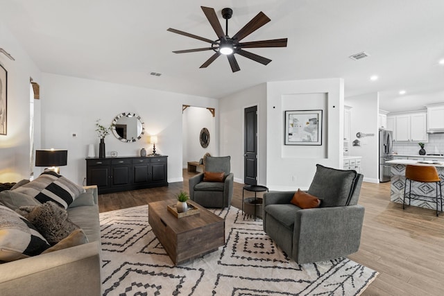 living room featuring light wood-style flooring, visible vents, and baseboards