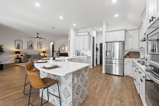 kitchen featuring a breakfast bar area, appliances with stainless steel finishes, open floor plan, wood finished floors, and light countertops