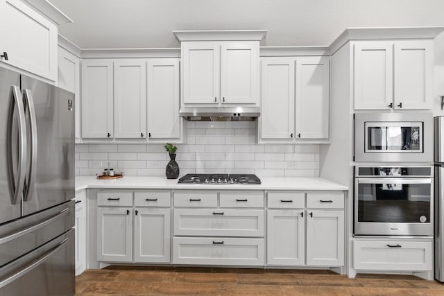 kitchen featuring appliances with stainless steel finishes, light countertops, under cabinet range hood, and decorative backsplash