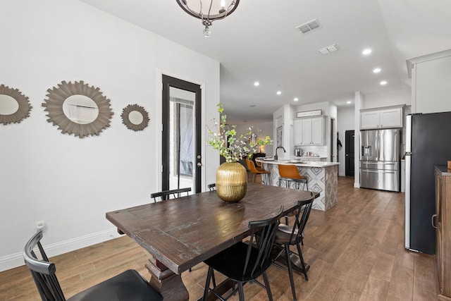 dining space with baseboards, wood finished floors, visible vents, and recessed lighting