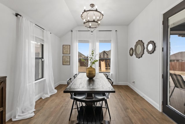 dining space featuring lofted ceiling, baseboards, a notable chandelier, and wood finished floors