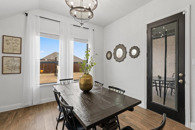 dining room featuring baseboards, wood finished floors, lofted ceiling, and a notable chandelier