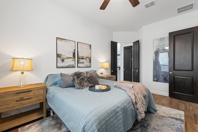 bedroom featuring a ceiling fan, baseboards, visible vents, and wood finished floors