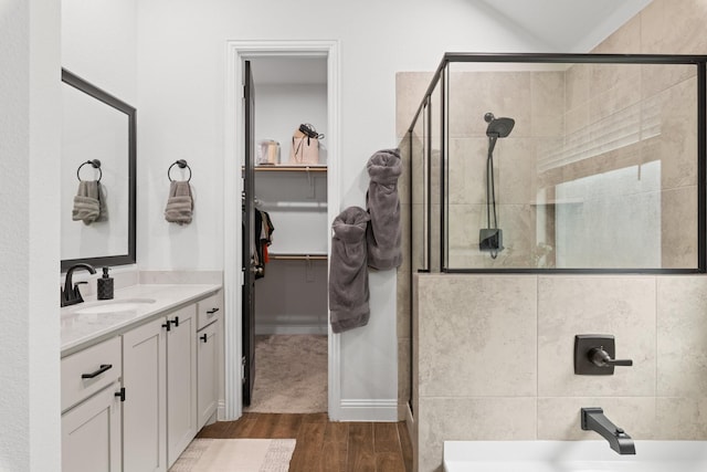 bathroom featuring a spacious closet, a shower stall, vanity, and wood finished floors