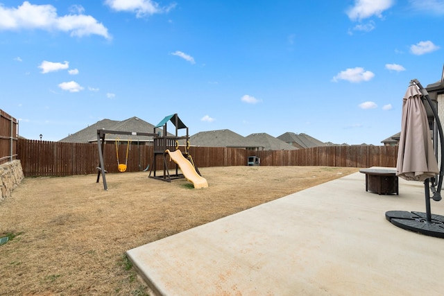 view of yard featuring a fenced backyard, a playground, and a patio