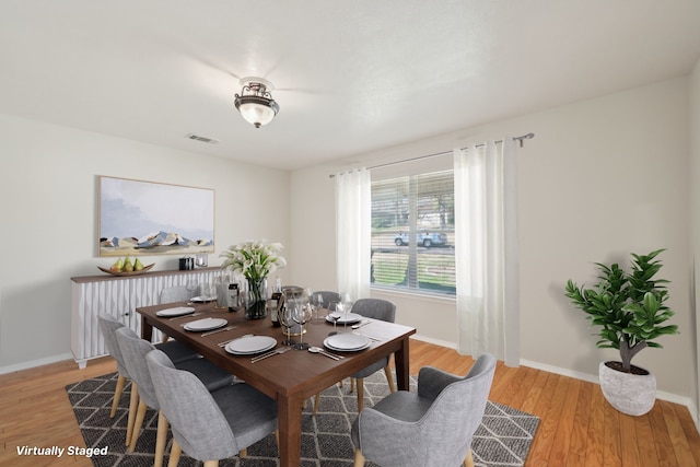 dining space with light wood-type flooring, visible vents, and baseboards