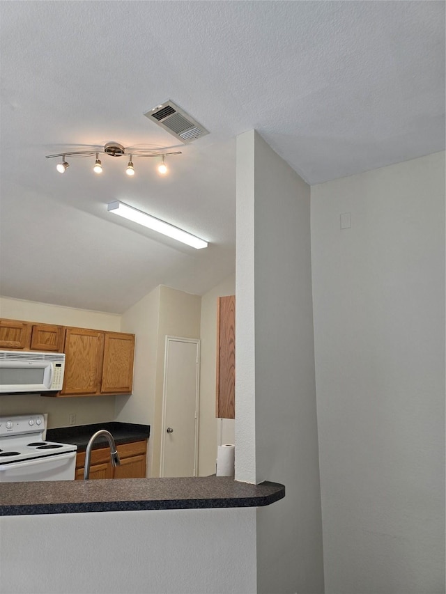 kitchen with white appliances, visible vents, dark countertops, brown cabinets, and a sink