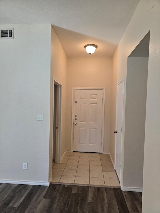 doorway featuring baseboards, visible vents, and wood finished floors