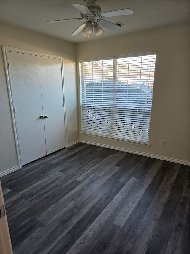 unfurnished bedroom with visible vents, a ceiling fan, dark wood finished floors, and a closet