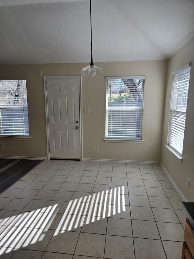 foyer entrance with vaulted ceiling, light tile patterned flooring, a wealth of natural light, and baseboards