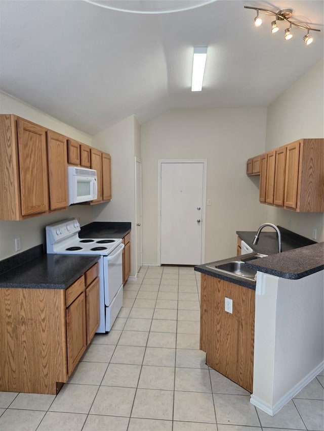 kitchen featuring white appliances, brown cabinetry, dark countertops, and a sink