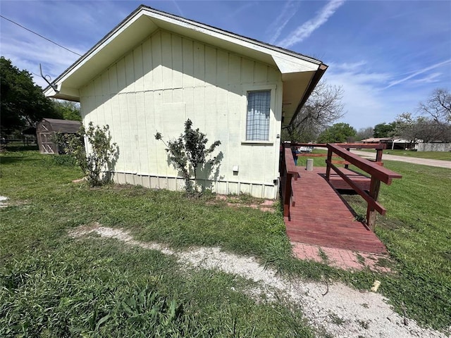 view of side of property with a storage shed, a lawn, and an outbuilding