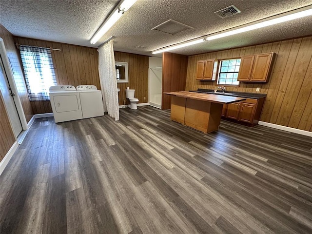 kitchen featuring washer and dryer, a healthy amount of sunlight, visible vents, and dark wood finished floors