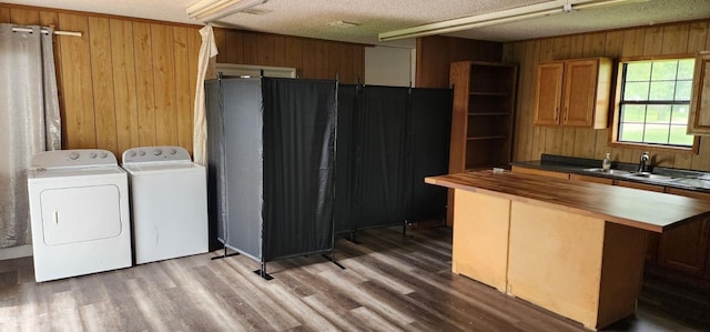 kitchen featuring wooden walls, a sink, wooden counters, light wood finished floors, and washing machine and clothes dryer