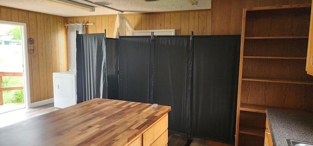 kitchen featuring washer / dryer, a healthy amount of sunlight, butcher block countertops, and wooden walls