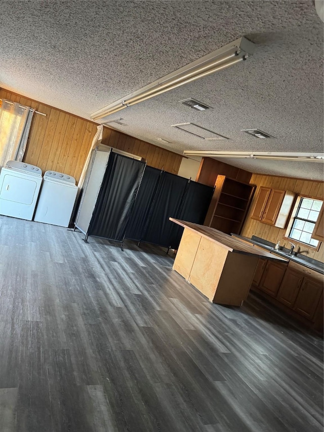 kitchen with dark wood finished floors, independent washer and dryer, wooden walls, and a textured ceiling