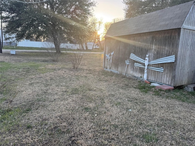 yard at dusk featuring a storage unit and an outbuilding