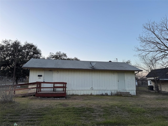 rear view of property featuring a deck, a lawn, and fence