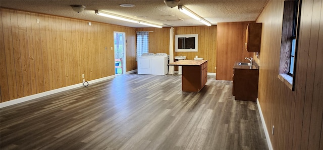 unfurnished office featuring a textured ceiling, dark wood-type flooring, a sink, baseboards, and washing machine and clothes dryer