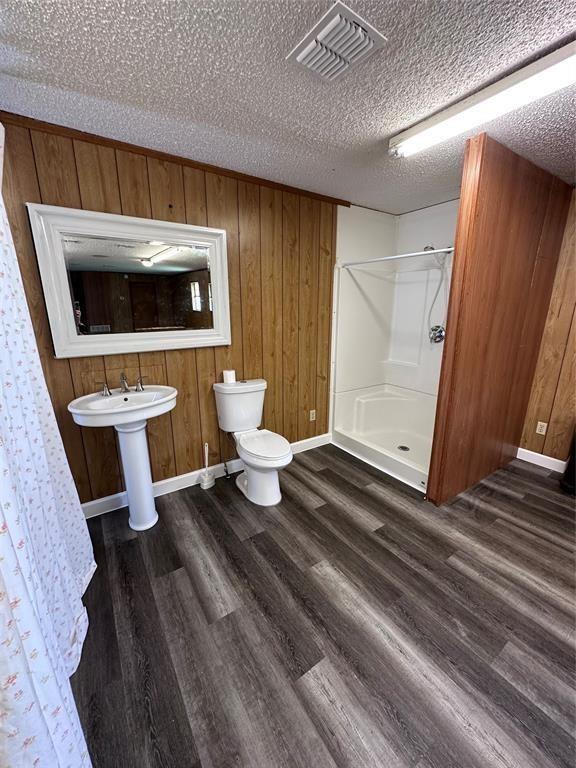 full bathroom with visible vents, a shower stall, toilet, and wood finished floors