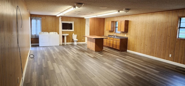 kitchen with washer and clothes dryer, light countertops, dark wood-type flooring, a sink, and a textured ceiling