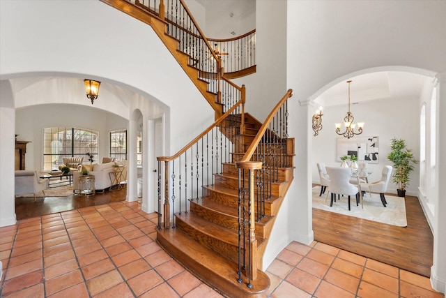 entrance foyer with a towering ceiling, a notable chandelier, and light tile patterned flooring