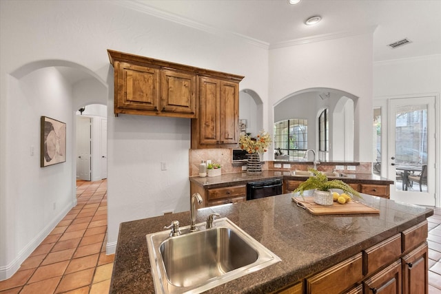 kitchen with black dishwasher, visible vents, brown cabinets, and a sink