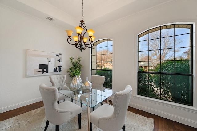 dining room with a notable chandelier, visible vents, ornamental molding, wood finished floors, and baseboards