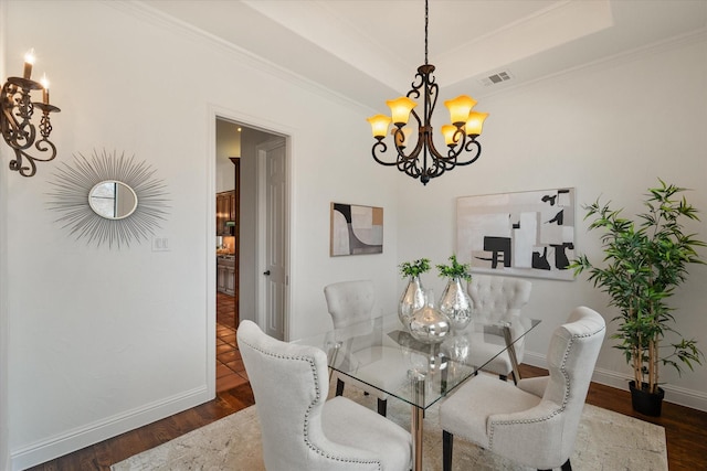 dining area with a chandelier, wood finished floors, visible vents, baseboards, and a tray ceiling