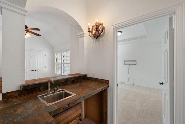 kitchen with arched walkways, carpet, dark countertops, a sink, and ceiling fan