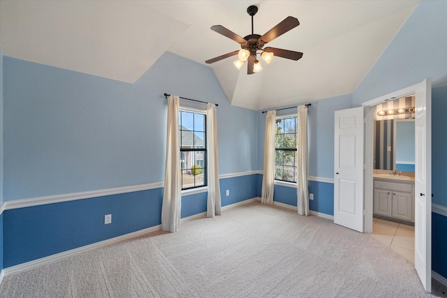 unfurnished bedroom with carpet floors, vaulted ceiling, a sink, ensuite bath, and baseboards