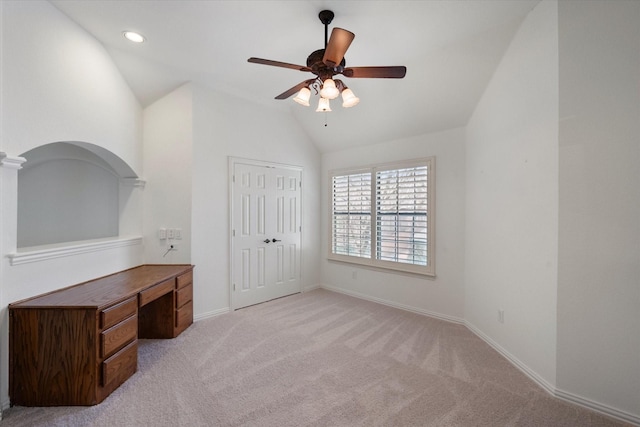 unfurnished office with lofted ceiling, ceiling fan, baseboards, and light colored carpet