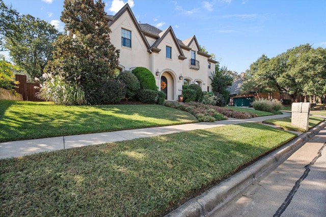 view of front of property featuring fence, a front lawn, and stucco siding