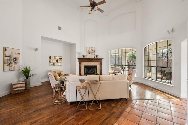 living area featuring baseboards, visible vents, a ceiling fan, wood finished floors, and a fireplace