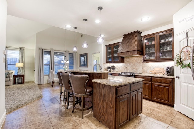 1005 Brendan Dr, Little Elm, TX 75068 - kitchen with premium range hood, high vaulted ceiling, a kitchen bar, backsplash, and stainless steel stove