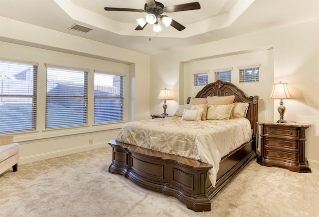 bedroom with baseboards, a raised ceiling, visible vents, and light colored carpet